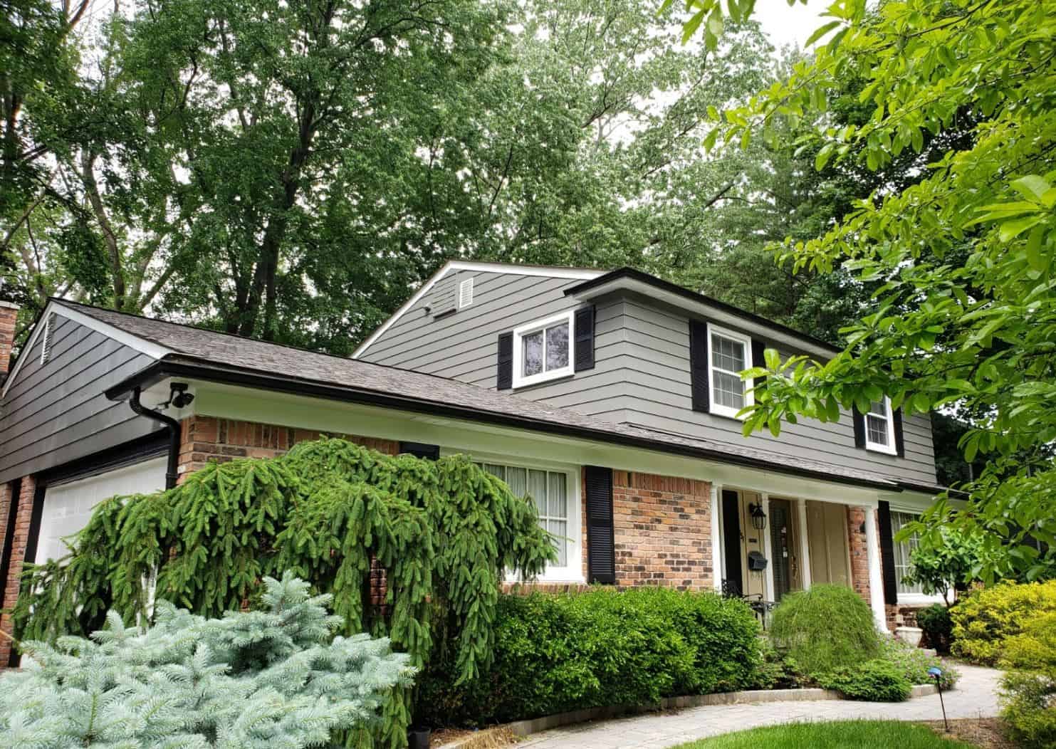 Stucco painted in light gray, with white trim and accents and brick